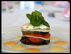 A plated starter by Penny Mardon Catering — layered vegetable stack with basil on a dressed plate