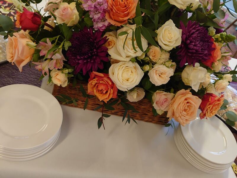 An autumn arrangement of roses, dahlias and chrysanthemums beside stacked white plates