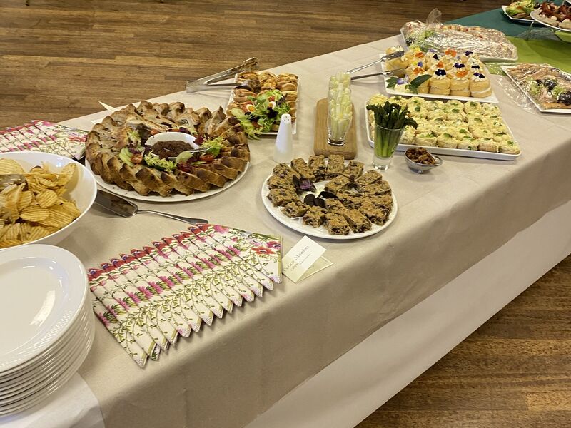 A buffet table laid with quiches, sandwiches, savoury tarts and a herb wreath