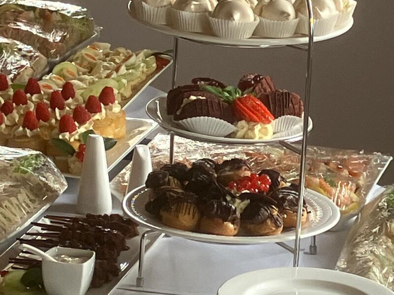 A tiered stand of chocolate cups, meringues and fruit tartlets beside stacked plates